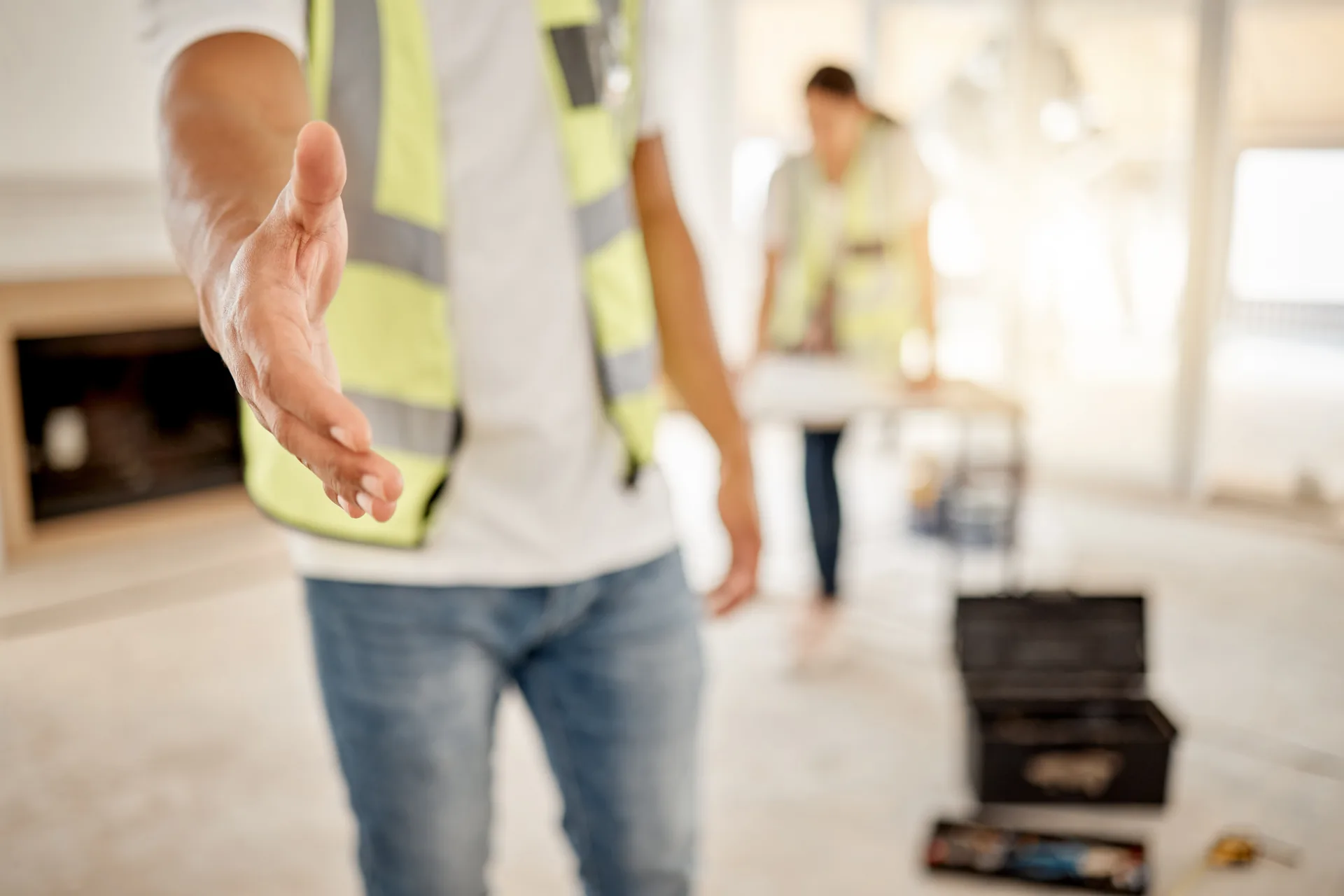 Tradie in hi-vis extending a handshake on a residential renovation site.